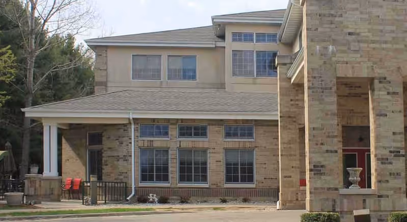 Two-story brick senior living campus building exterior with windows and entrance.