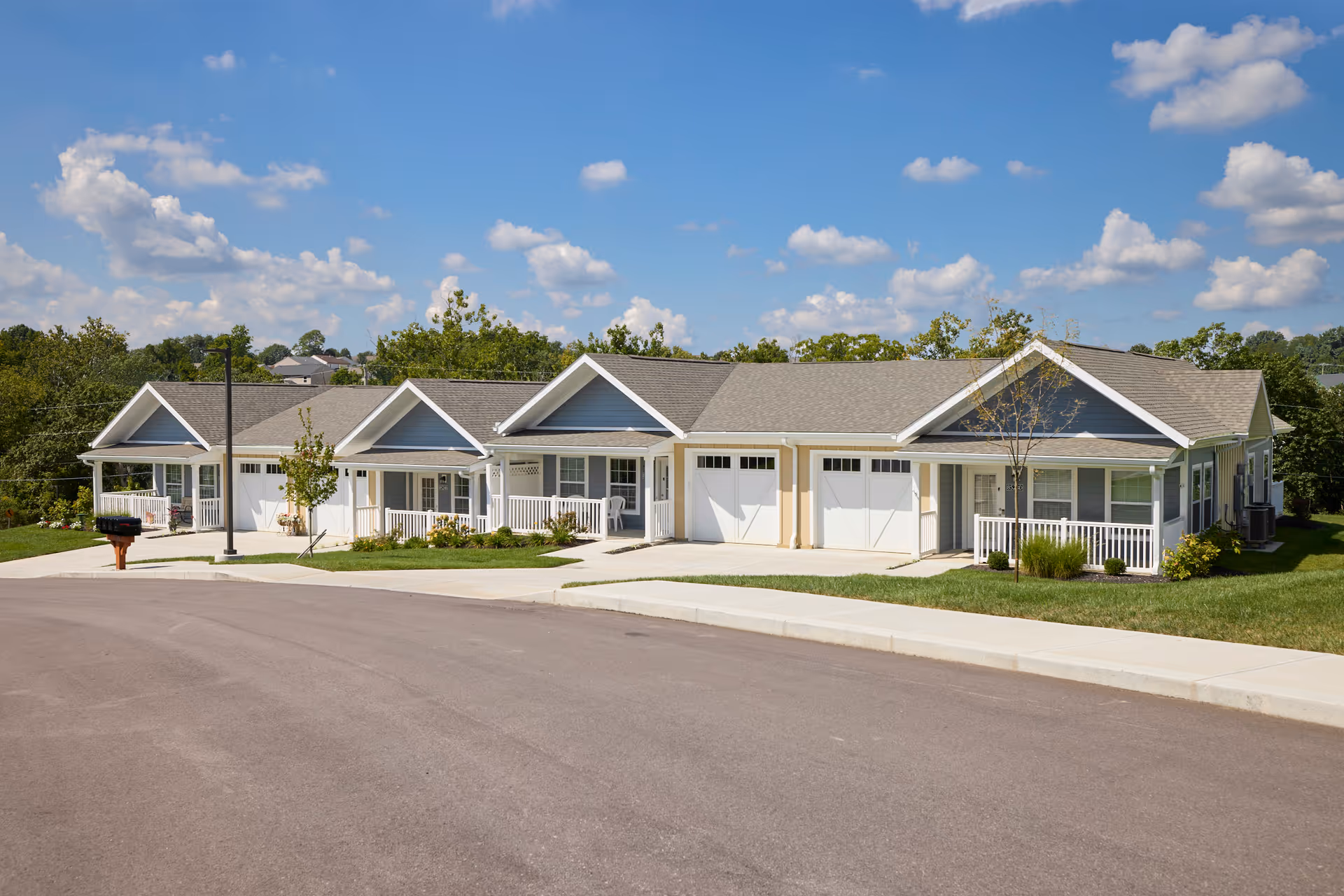A single-story senior living building with multiple front garages and manicured lawn.
