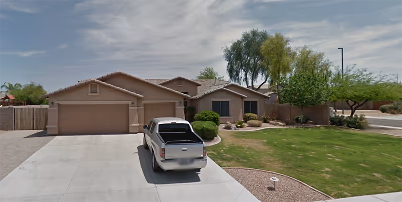 Front view of a beige, single-story house with a two-car garage and a parked white pickup.