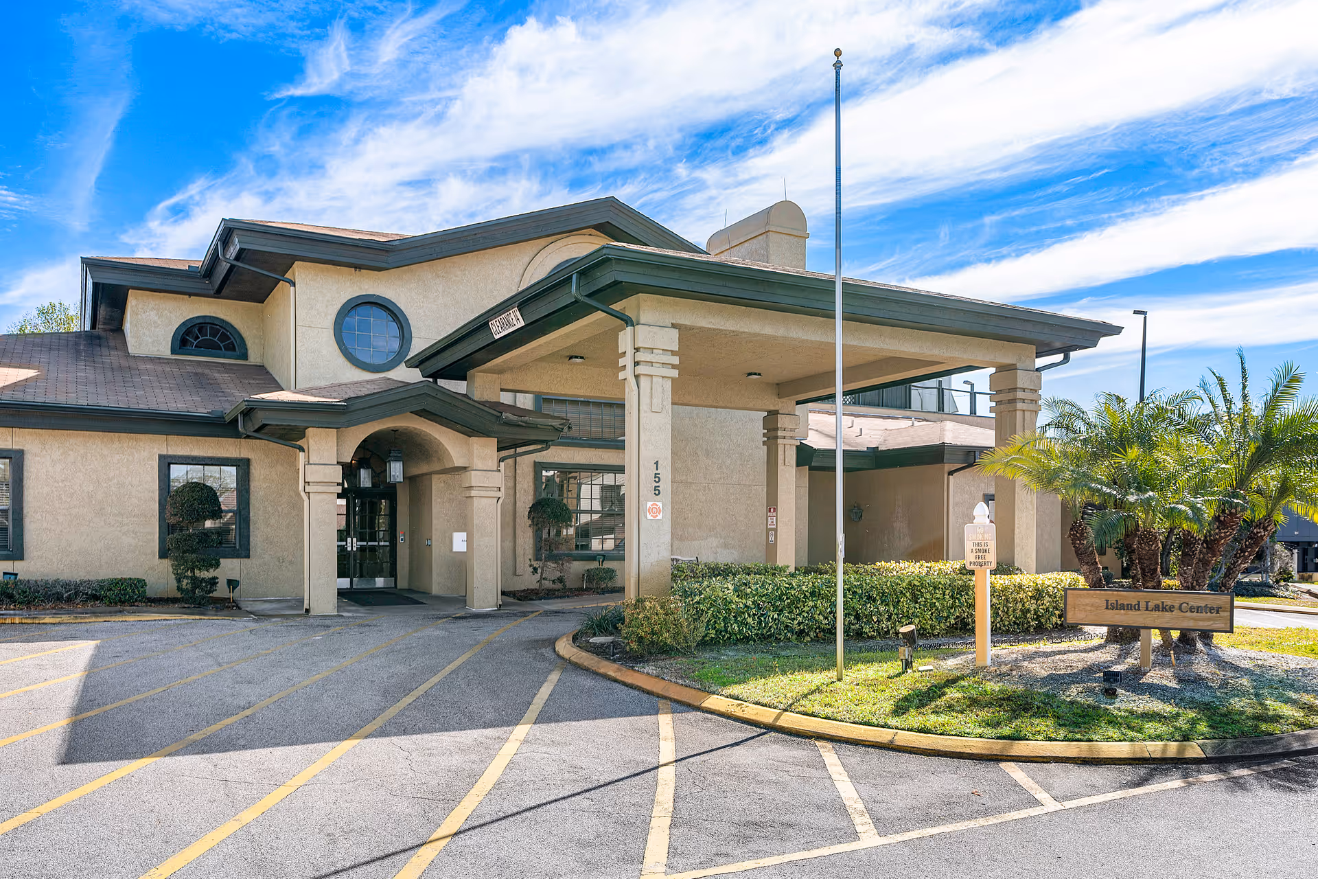 Front entrance of the Island Lake Center building featuring a covered porte-cochere, circular driveway, and landscaping.