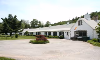 Long white single-story retirement home with circular driveway and landscaped center island.