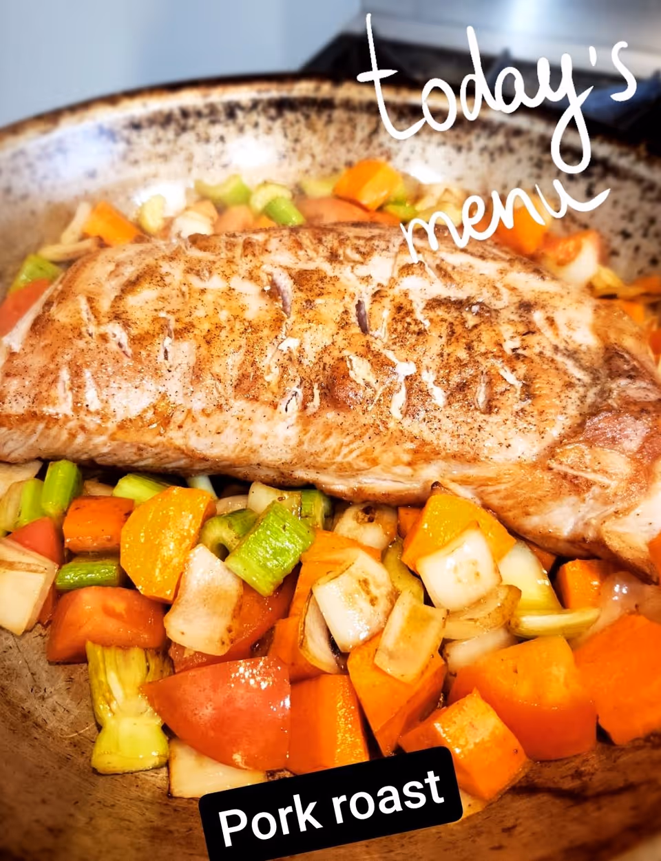 A cooked pork roast placed on a bed of mixed cooked vegetables including carrots, celery, onions, and tomatoes in a pan. The image has text overlays that read 'today's menu' and 'Pork roast'.