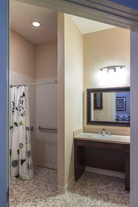 Bathroom featuring a tiled shower, patterned curtain, and a dark wood vanity with mirror