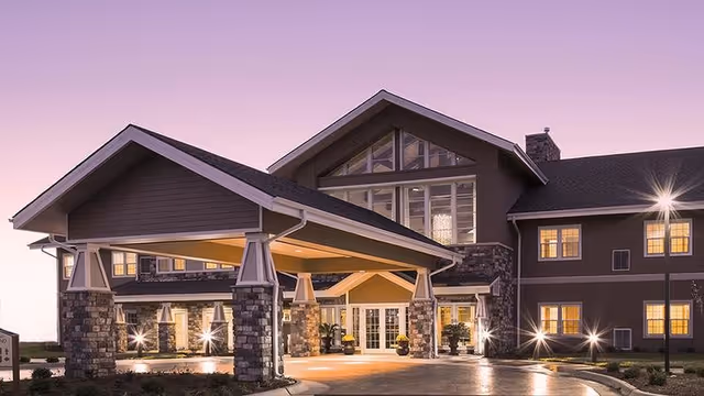 Exterior view of The Oxford Grand assisted living facility with a stone-entry portico at dusk