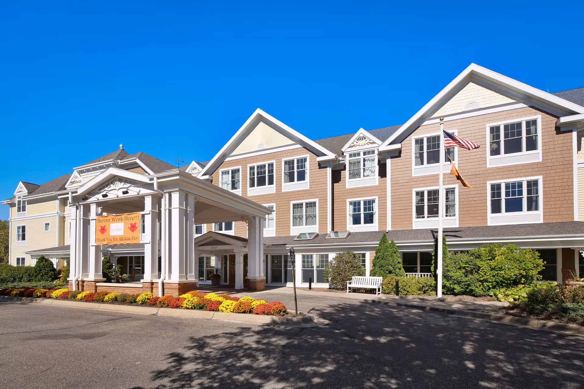 Exterior view of a senior living facility entrance with a covered drop-off and landscaping.