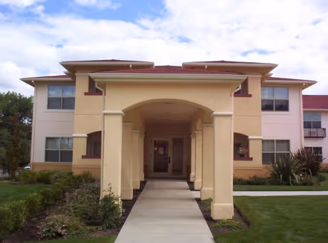 Front view of a beige senior living facility with a covered walkway entrance.