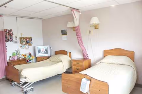 Two single beds with a nightstand in a shared patient bedroom.