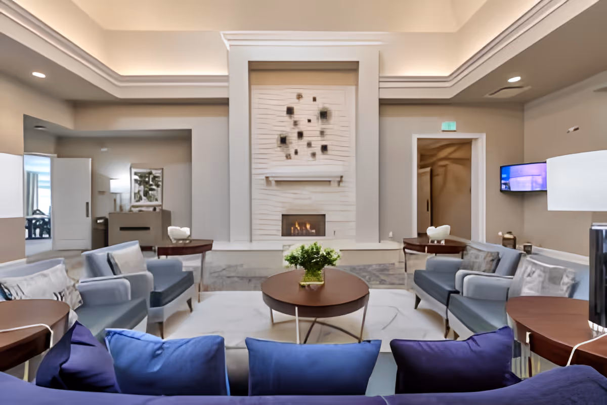 Spacious elegant lounge with sofas and chairs arranged around a central coffee table in front of a fireplace.