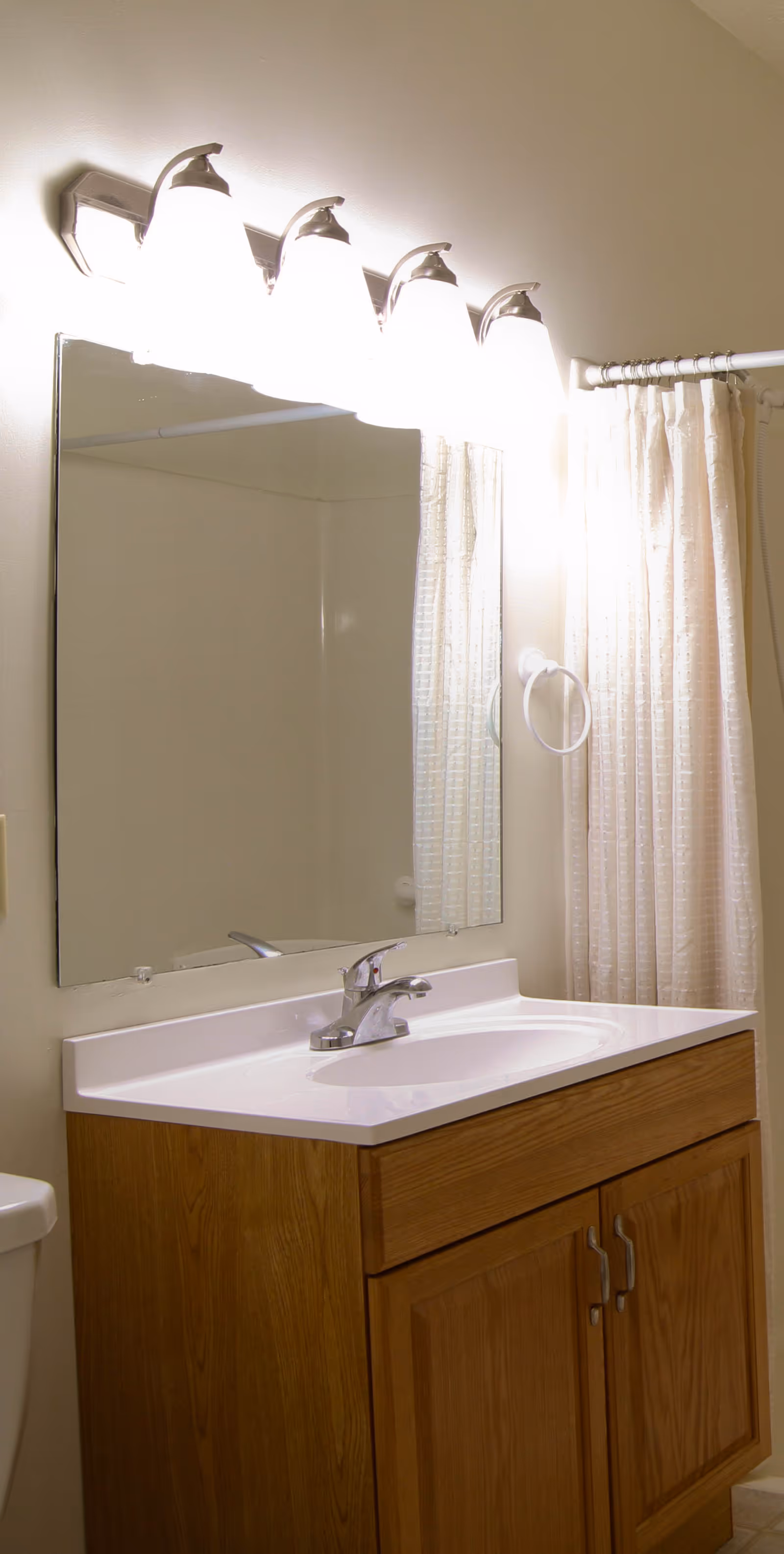 Bathroom vanity with sink, mirror, overhead lights, and a shower curtain.