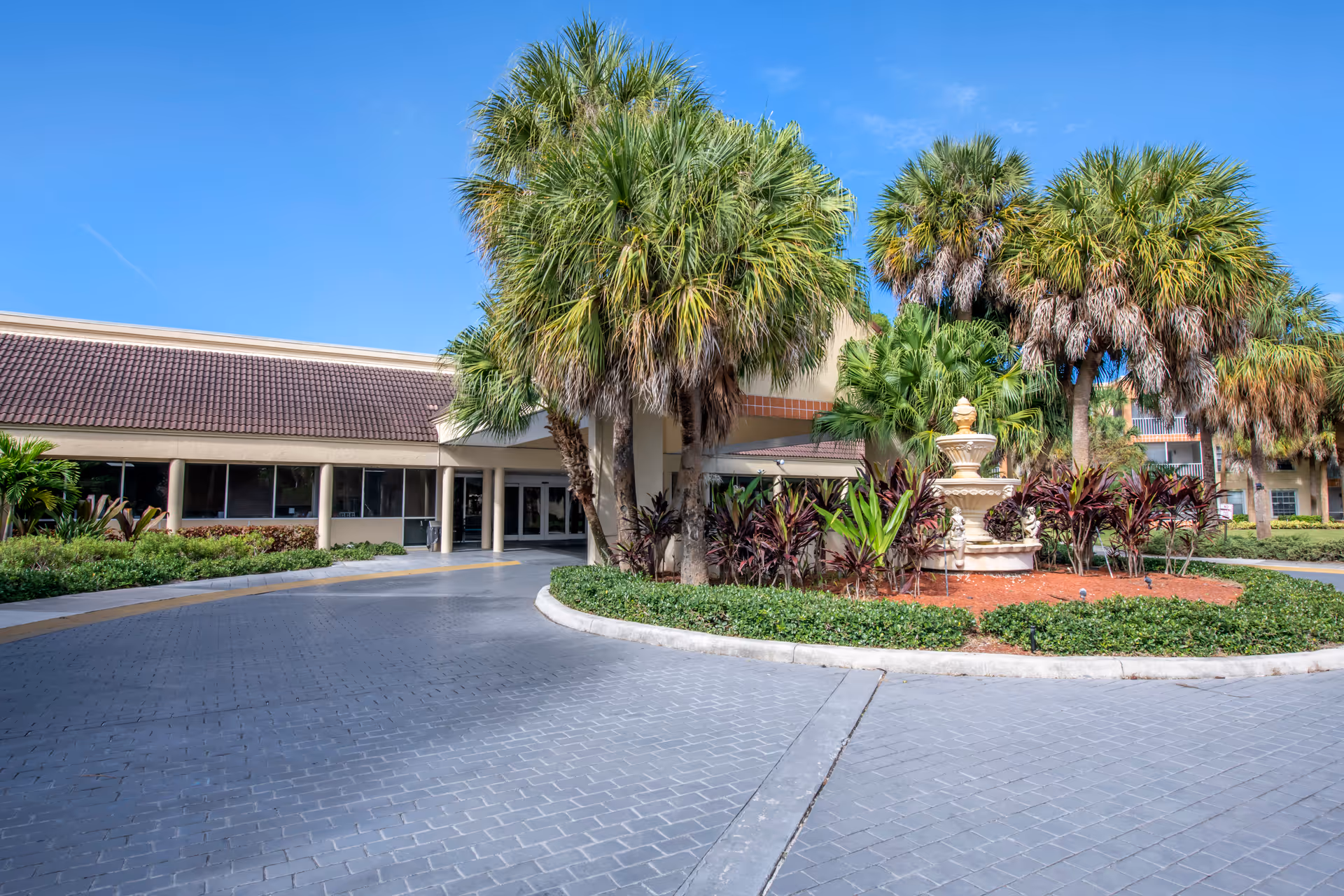 Exterior view of Brookdale West Palm Beach entrance with palm trees and landscaping