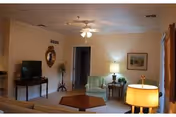 Cozy living room with sofas, an armchair, coffee table, TV, lamps, framed art, and a ceiling fan.