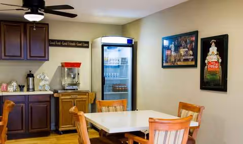Interior dining room with a table, chairs, cabinets, a beverage fridge, and wall art.