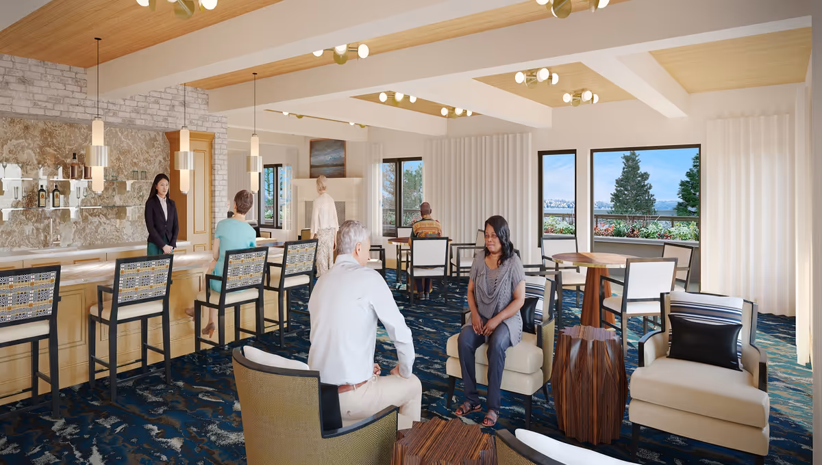 Bright communal lounge featuring a bar, multiple seating areas, and large windows with greenery, with a few people seated and staff at the counter.