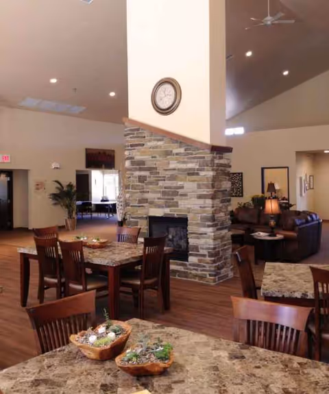 Interior dining area with a stone fireplace, tables, and wooden chairs.