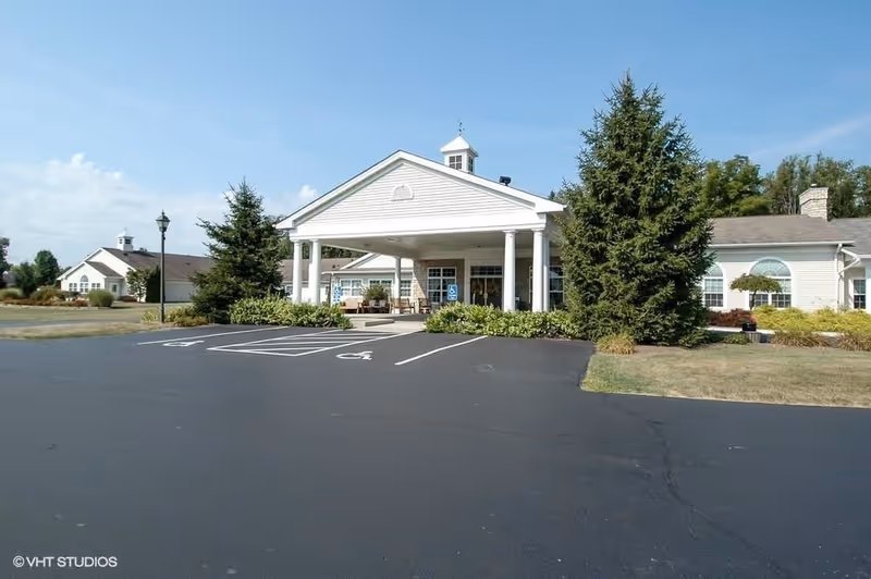 Front exterior of Whispering Pines Village senior living facility with entrance and parking.