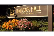 Outdoor sign for Hancock Hall Floral Care Center surrounded by colorful flowers and greenery.