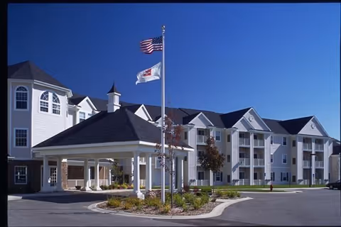 Swanhaven Manor retirement community exterior with entrance, flagpoles, and a driveway.