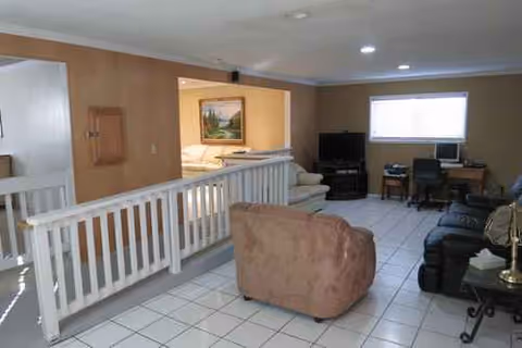 Interior common area of Palms Place Home for the Elderly with sofas, TV, and tiled floor.