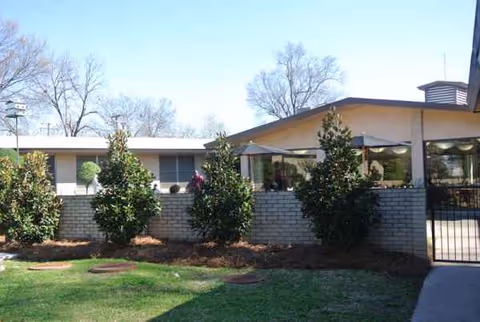 Exterior view of Southern Oaks Nursing & Rehabilitation Center with brick wall, trees, and gate.