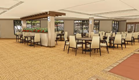 Spacious dining area with multiple round tables and beige cushioned chairs arranged neatly on a carpeted floor. The room features large windows allowing natural light to enter, and a decorative wooden beam structure with plants underneath separates part of the space.