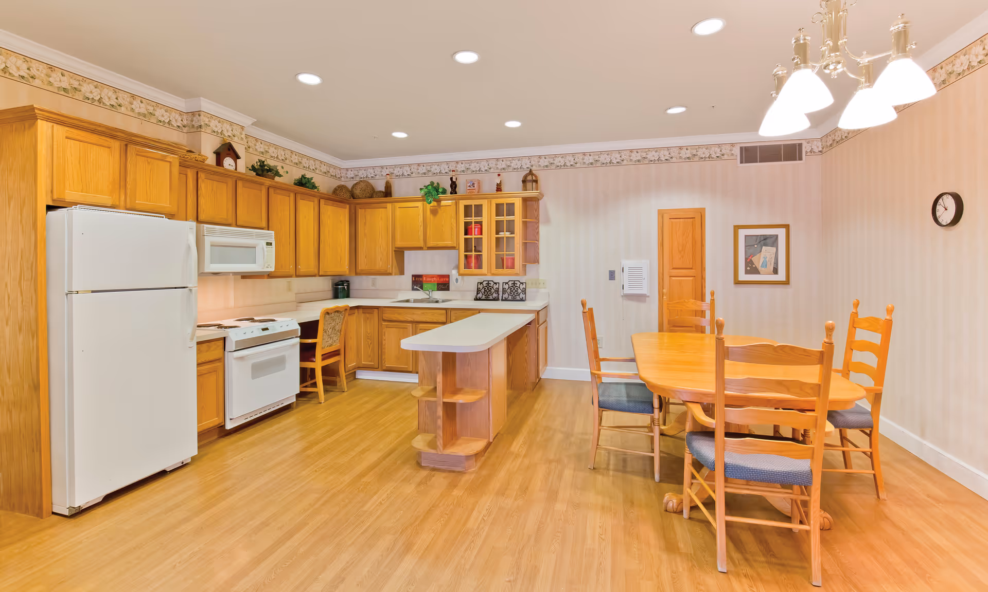 Spacious kitchen and dining area with oak cabinets, a center island, white appliances, and a wooden dining table with chairs.