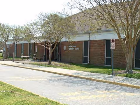 Exterior of a brick facility with trees and benches along a sidewalk