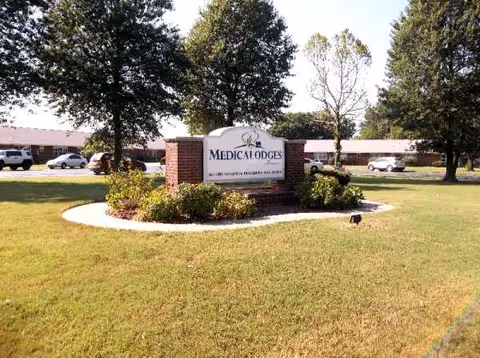 Exterior view of Medicalodges Frontenac with a landscaped sign and brick building behind.