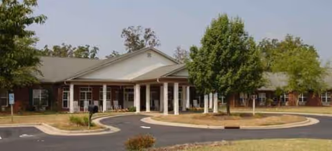 Front exterior of Brookdale Skeet Club assisted living entrance with drive, trees, and landscaping.