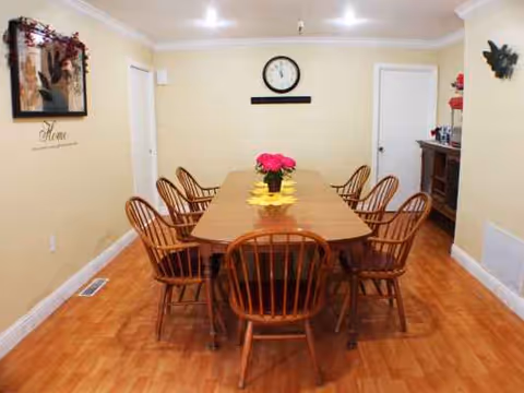 A long wooden dining table with chairs in a pale yellow dining room.
