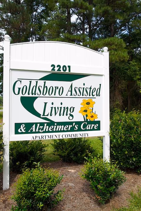 Outdoor sign for Goldsboro Assisted Living & Alzheimer's Care with greenery.