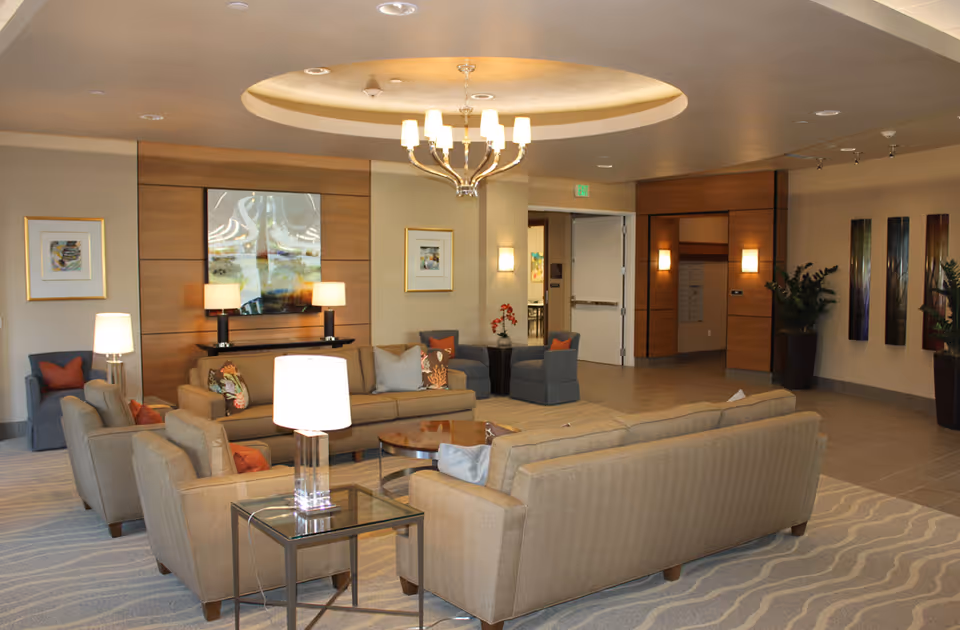 Spacious modern lounge with sofas, armchairs, coffee tables, lamps and artwork under a decorative ceiling light.