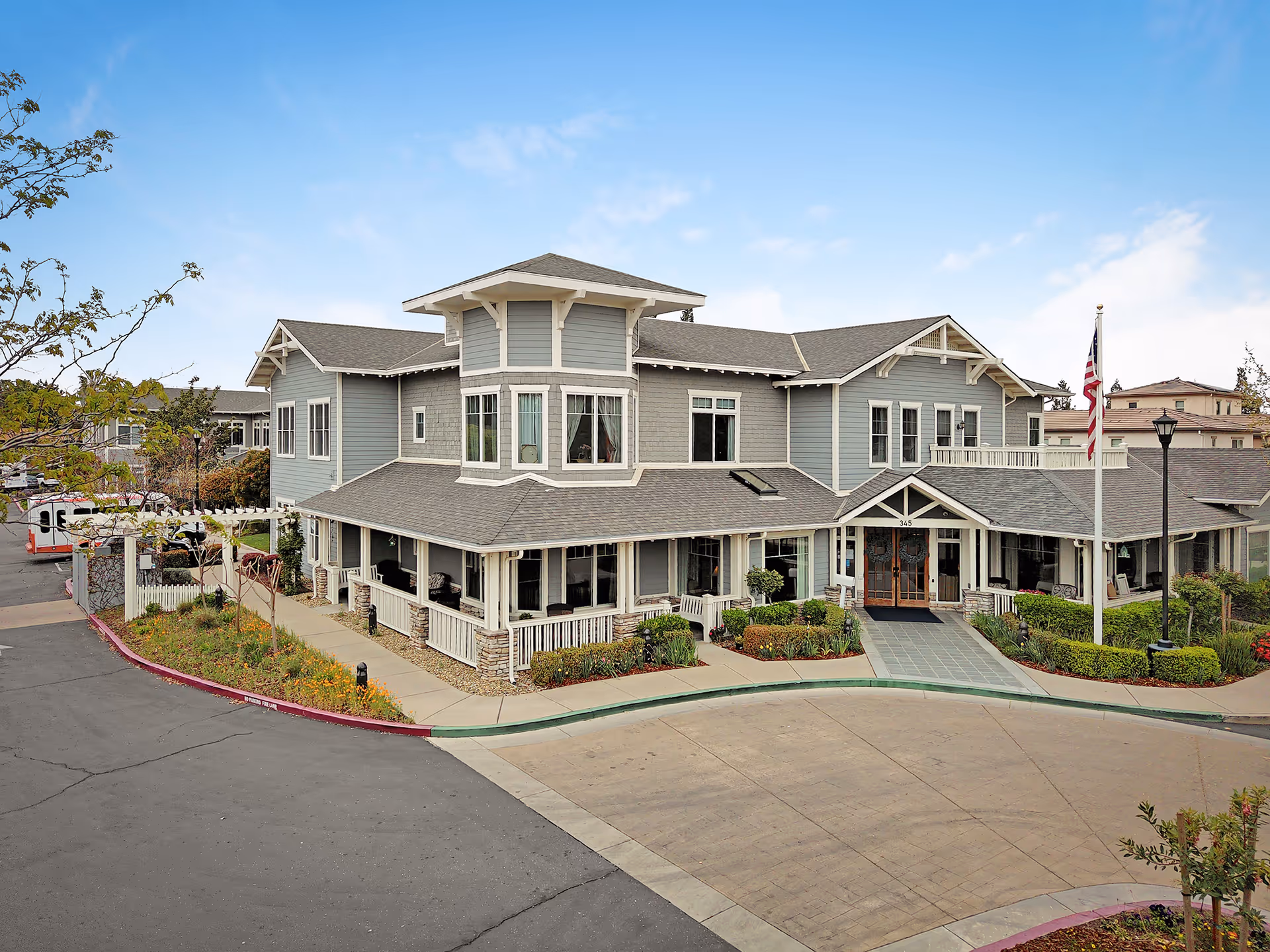 Blue-gray senior living facility exterior with wraparound porch and entrance