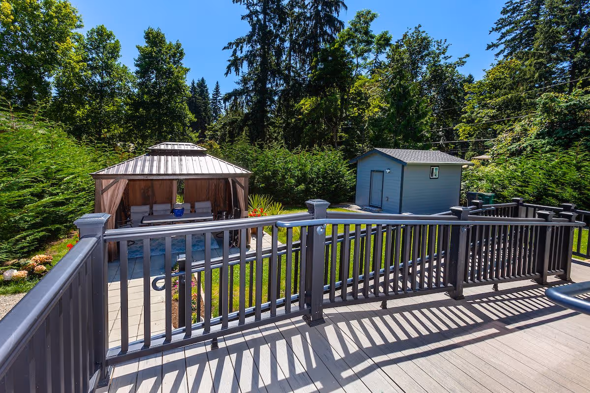 View from a deck over a backyard with a gazebo, small shed, and surrounding trees and lawn.
