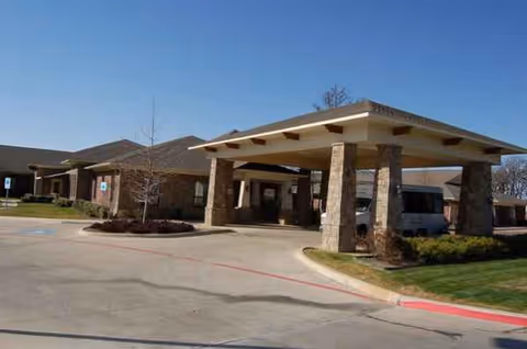 Exterior view of Keller Oaks Healthcare Center entrance with covered driveway and stone columns.
