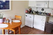 Small kitchenette and dining nook with a round wooden table and two chairs, mini-fridge, microwave, sink, and countertop appliances.