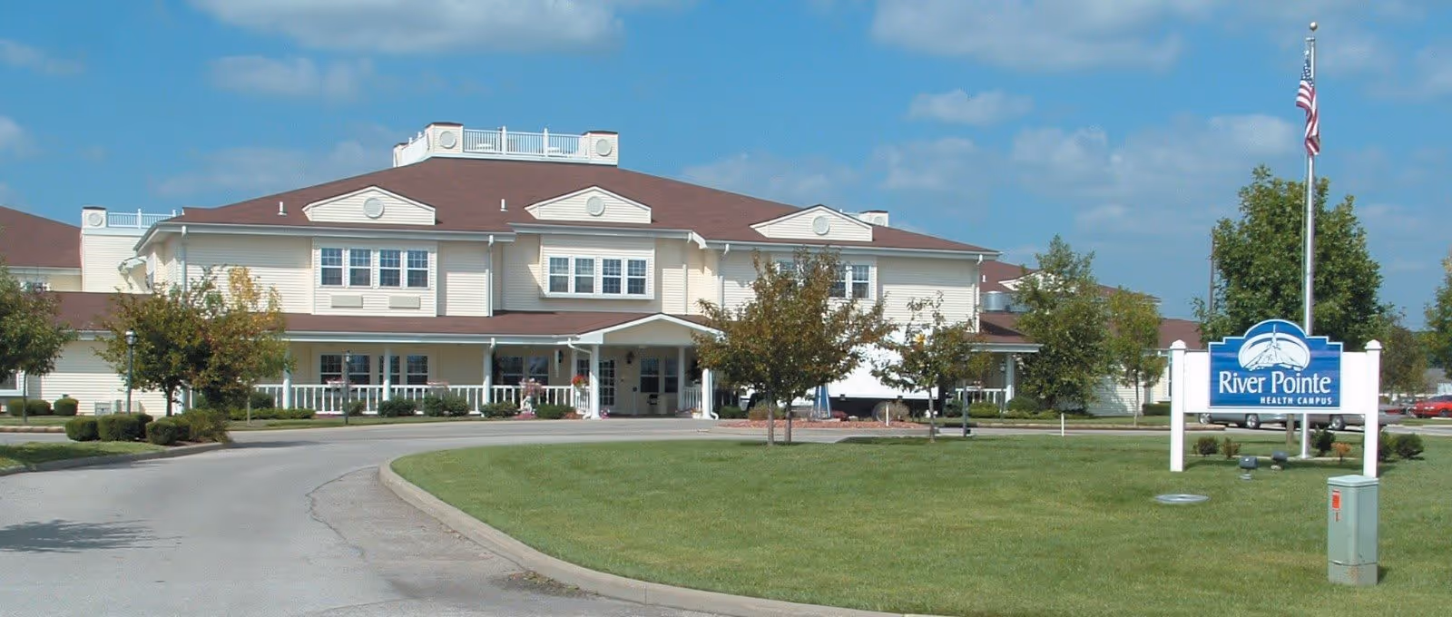 Front exterior of the River Pointe Health Campus building with a driveway, lawn, and a sign.