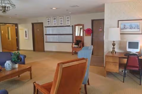 Spacious senior living lobby with seating, a desk, and wall-mounted bulletin board.