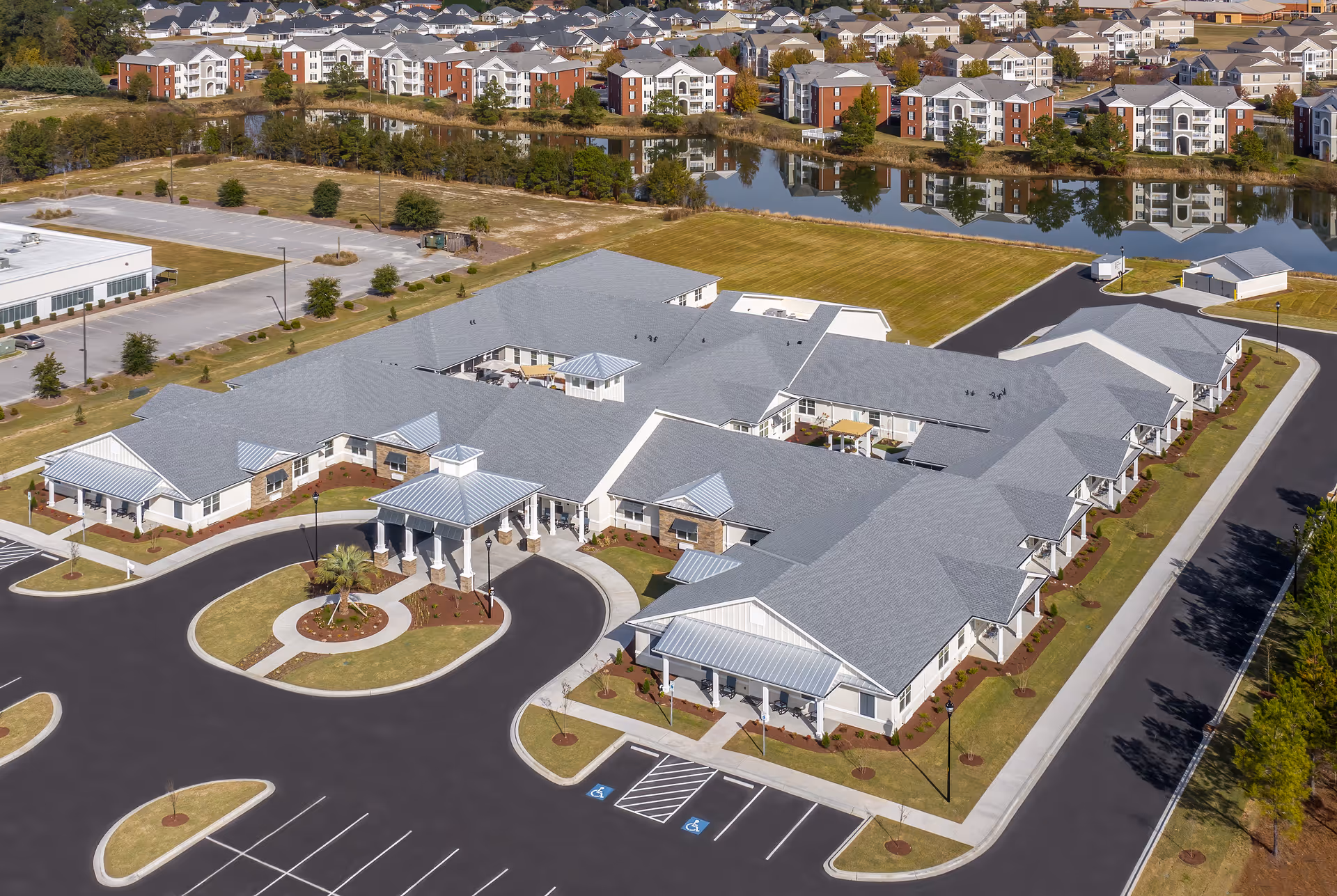 Aerial view of a large senior living campus with connected white-roofed buildings and a circular driveway.