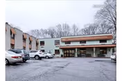 Front exterior of Westgate Hills Rehabilitation & Nursing Center with parked cars and bare trees.