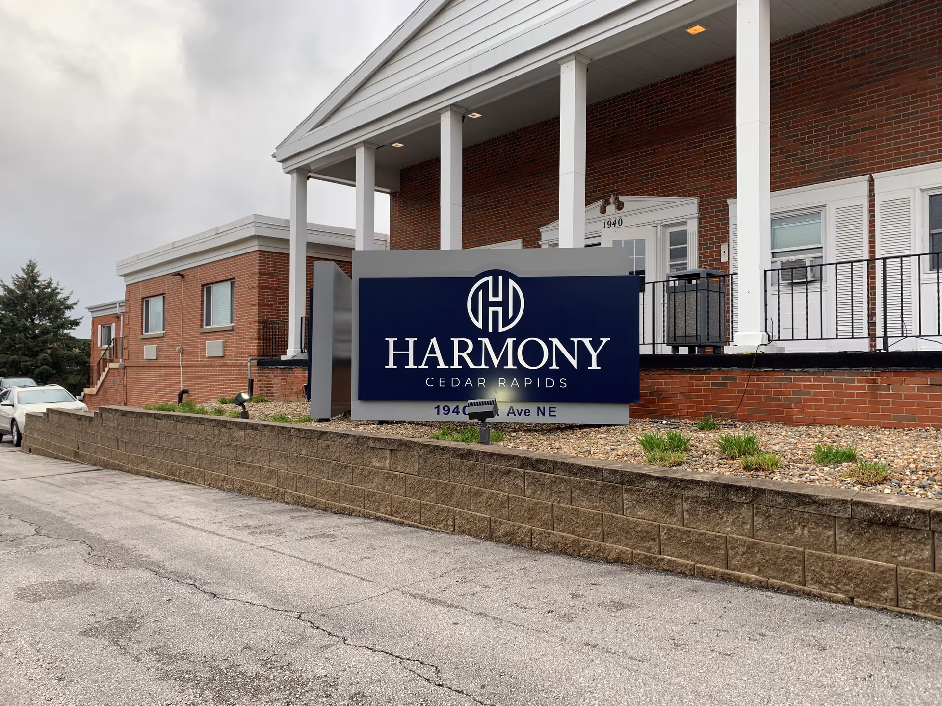 Front exterior of a brick building with a prominent blue sign reading 'Harmony Cedar Rapids' near the entrance.