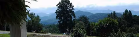 Scenic outdoor view with hills, trees, and distant mountains beyond a care home
