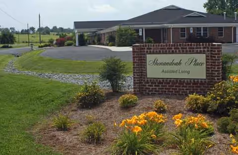 Brick sign reading Shenandoah Place Assisted Living with landscaped flowerbeds and a low, single-story building behind.