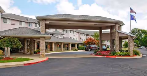 Arbor Glen entrance with a covered porte-cochère and parking area.