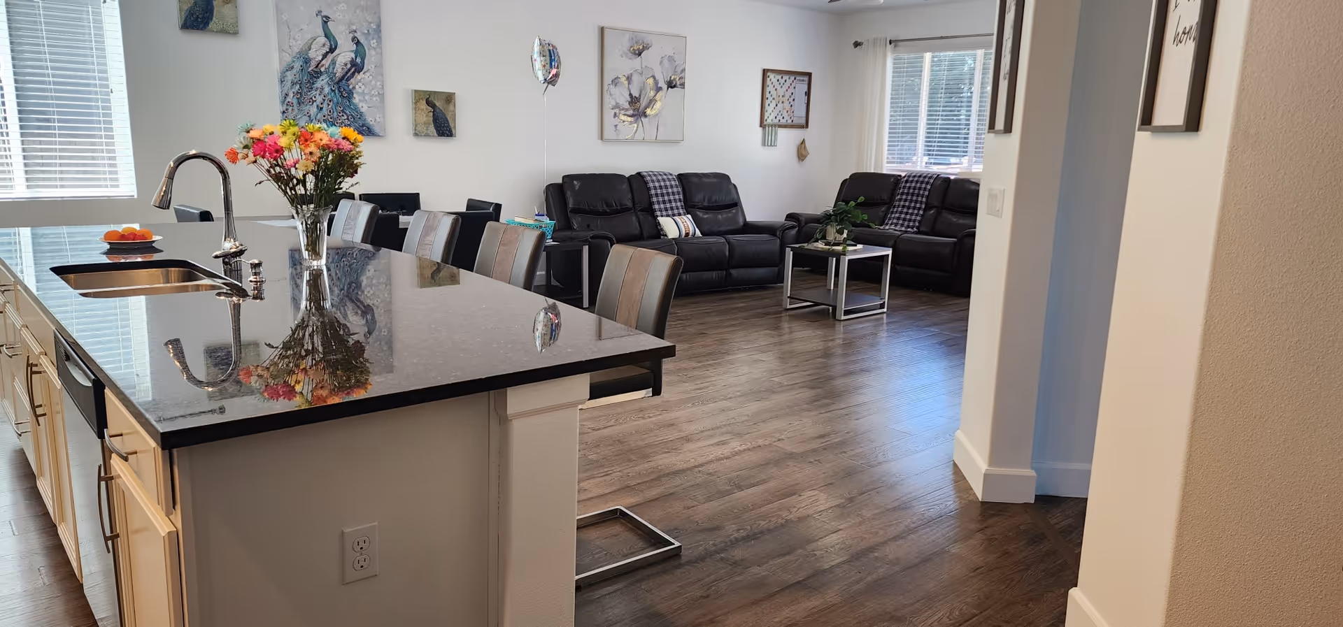 Open-concept common area featuring a kitchen island, leather seating, and wall art.