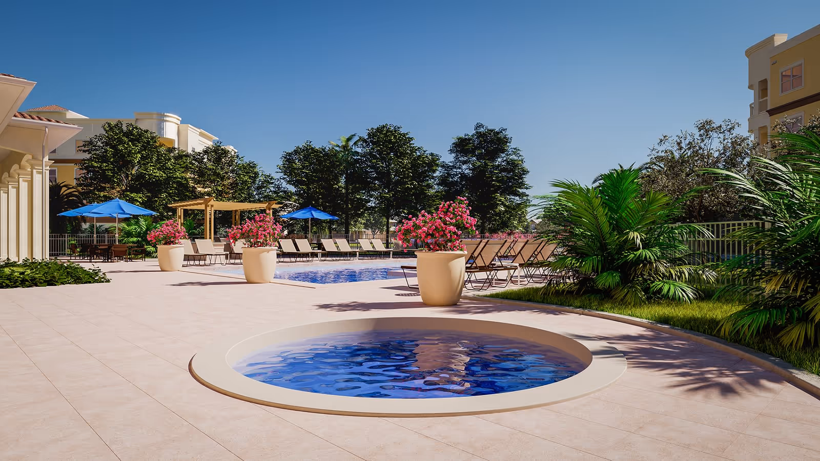 Outdoor pool area at The Alloro at University Groves featuring a small circular hot tub in the foreground, a larger swimming pool with lounge chairs and blue umbrellas, surrounded by potted pink flowers, green plants, and trees under a clear blue sky.