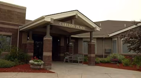 Entrance to Carlton Place senior living with a covered walkway and benches.