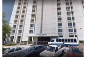 Front exterior of a tall multi-story building with an entrance canopy reading 'Baptist Towers' and several cars and a van parked in front.