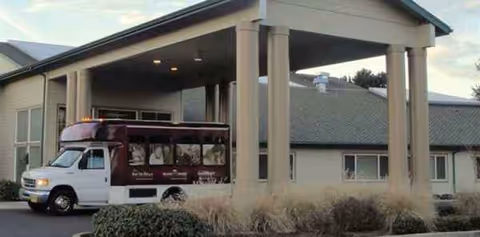 Exterior view of Green Valley Rehabilitation Health Center with a parked shuttle bus at the entrance.