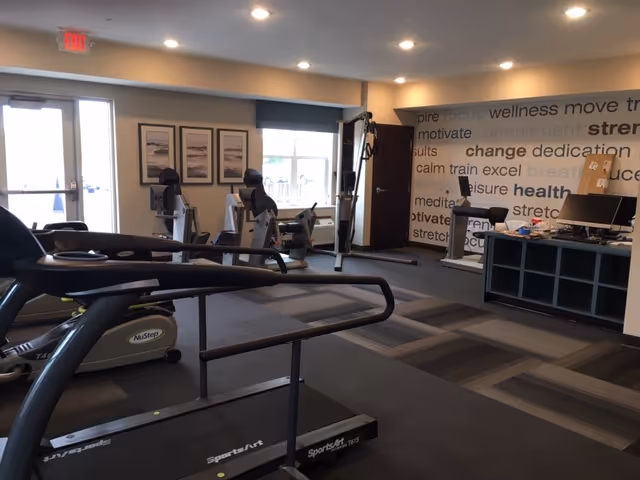 Fitness room with treadmills, recumbent bikes and strength equipment and motivational word-art on the wall.