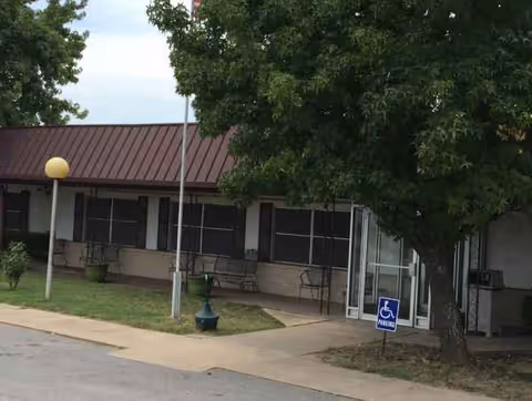 Exterior view of Jan Frances Care Center, with benches, trees, and a front entrance.